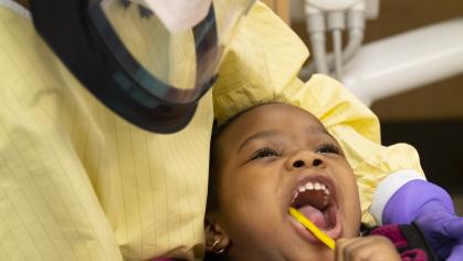 dentist helping a child brush their teeth